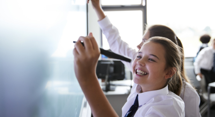 Girls Writing On Board At School