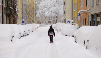 Person walking in the middle of a snowy city street.