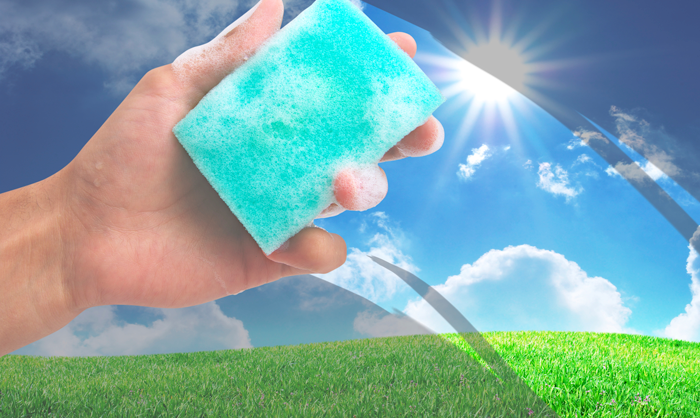 Hand holding a sponge cleaning an image of a sunny rolling hills landscape.