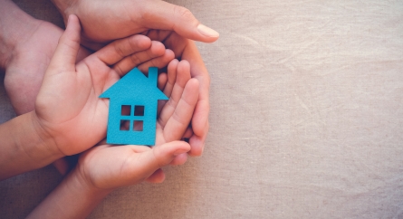 Adult and child hands holding paper house.