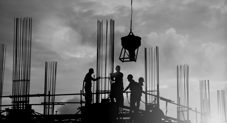 Construction workers up high on a site with a crane in shot.