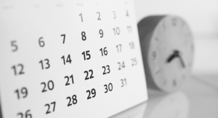 Close up of calendar and a clock on a table.
