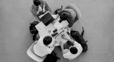 Over-head shot of students studying at a small round table.