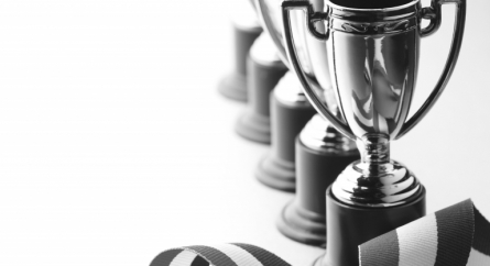 A row of trophies and a red, white, and blue ribbon.