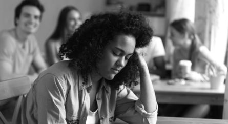 Mixed race girl sitting alone separately from other students