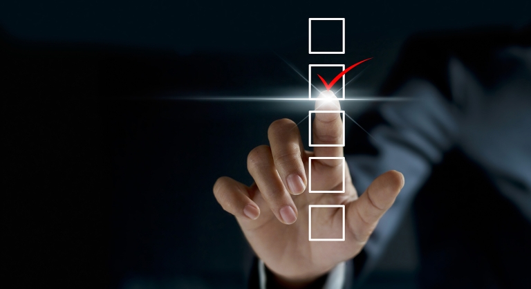 Businessman checking mark on checklist with a red marker on dark background.