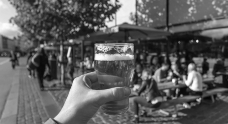 Beer in someone's hand by an outdoor eating establishment