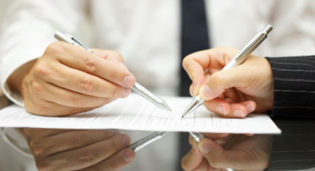 Business man is pointing woman where to sign document