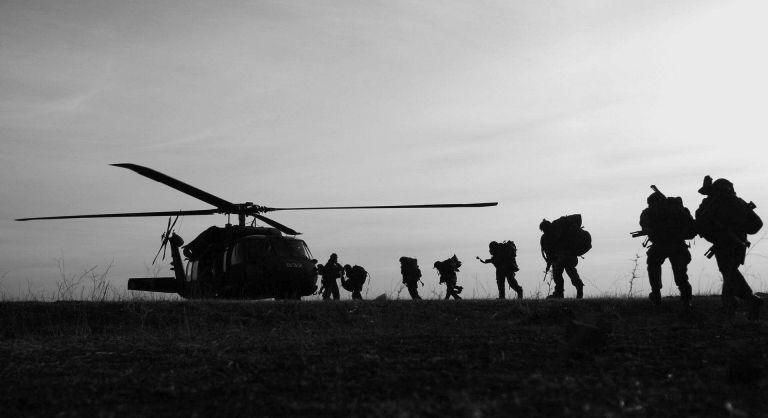 Military people boarding a helicopter.
