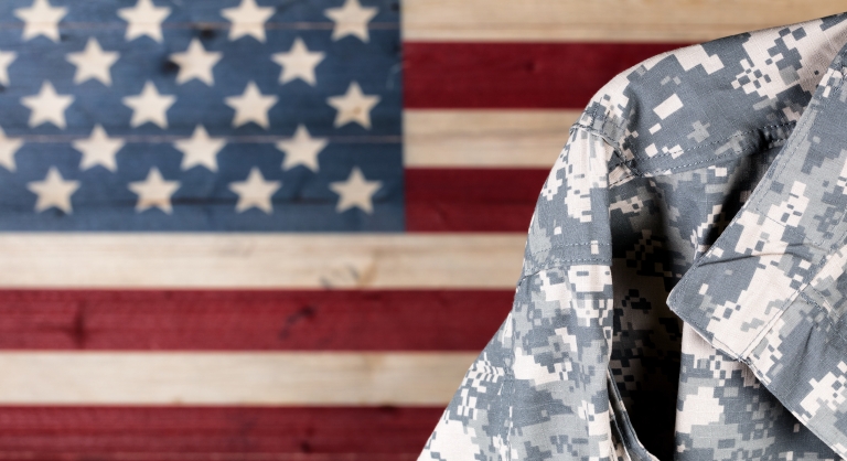 Close-up of military uniform with painted rustic boards of USA flag in background.