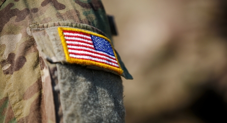 Close-up of an American flag patch on the sleeve of a military uniform.