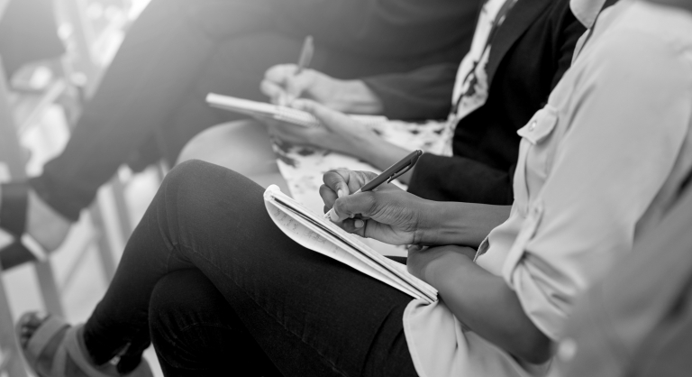 Group of people writing in notebooks at a training,