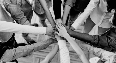 Team standing in a circle with their hands in a pile in the center.