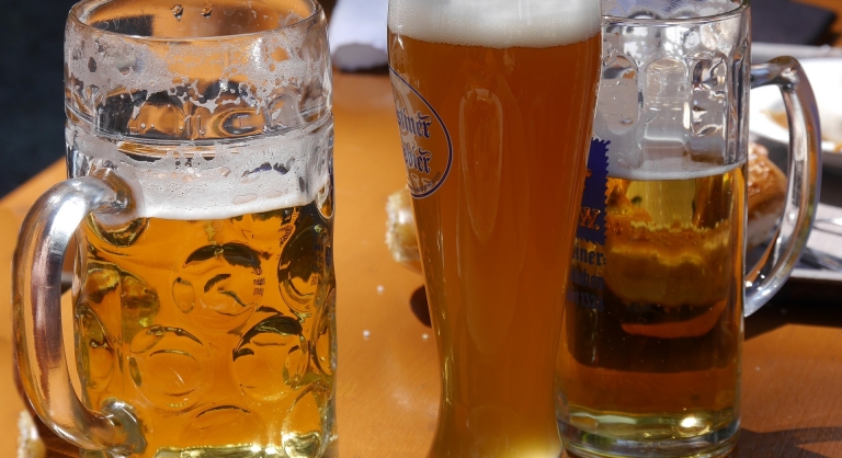 Different sized glasses and mugs of beer.