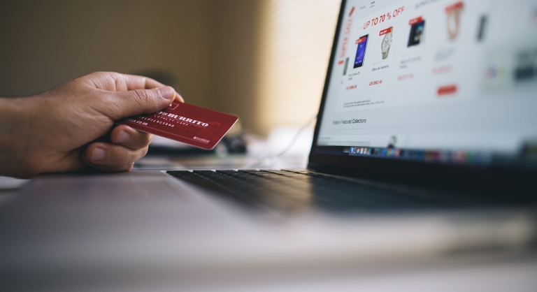 Person holding a credit card while online shopping.