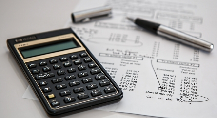 Calculator and pen on a paper where someone was calculating budget with the words "can we do this?" written on the bottom.