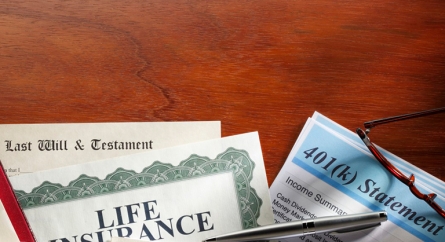 A Last Will & Testament, a Life Insurance Policy, and 401k Statement on a desk.