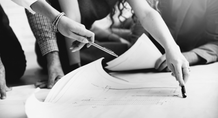 Group of three gathered around a blueprint.