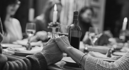 Family holding hands before eating a holiday dinner.