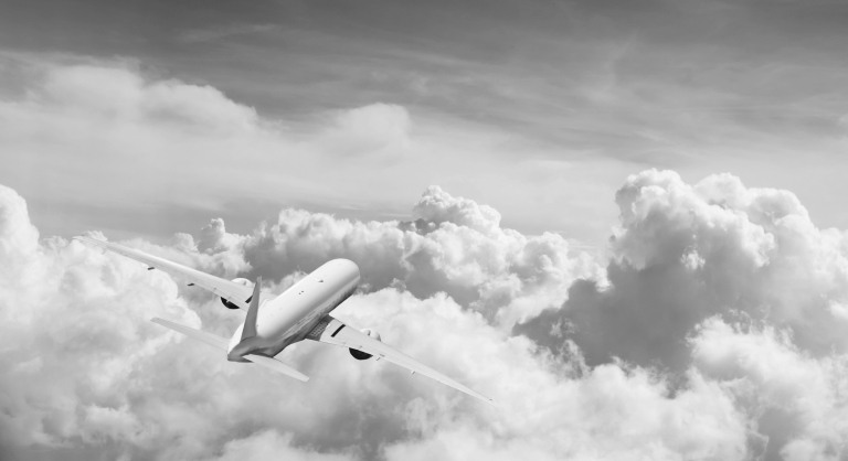 Back view of commercial airplane flying above clouds.