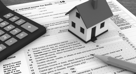 U.S. Individual Income Tax Returns with a small house on it next to a calculator.