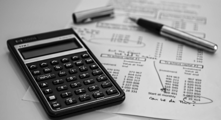 Calculator and pen on a paper where someone was calculating budget with the words "can we do this?" written on the bottom.