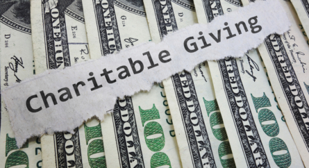 one hundred dollar bills and a note that says charitable giving