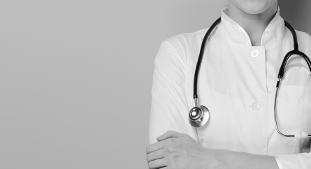 Healthcare professional with a stethoscope standing with their arms crossed.