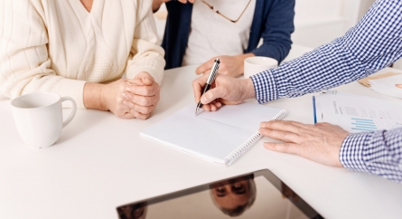 Business person meeting with clients drawing out a diagram for them.