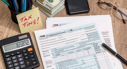 Tax form with calculator, money and pen on a table.
