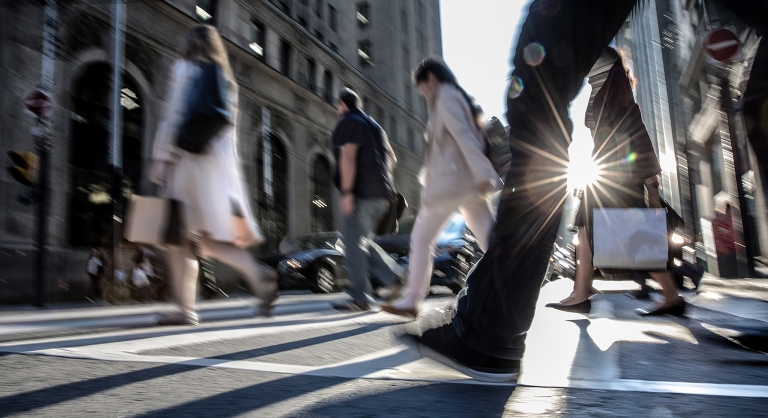 Group of people in a crosswalk on a busy city street.