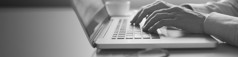 Close-up of hands typing on a laptop.