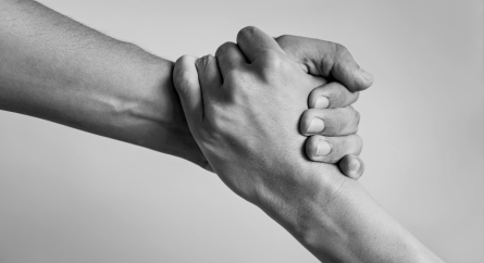 Close-up of interlocking hands as if one person is helping another stand up.