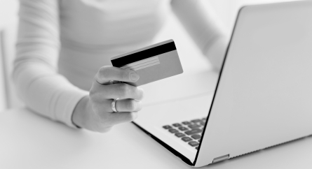 Person holding a credit card while using a laptop.