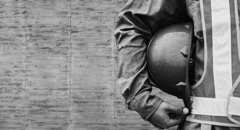 Construction worker standing with hardhat under their arm.