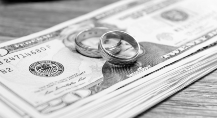 Wedding rings on a stack of 20 dollar bills.