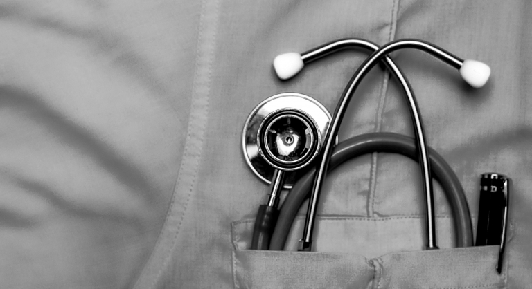 Close-up of a stethoscope and pen in a doctor's shirt pocket.