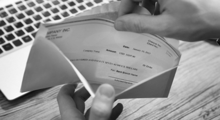 person's hand removing paycheck from an envelope