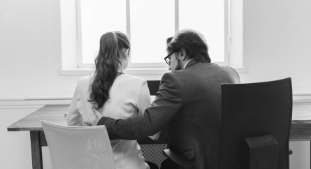 Man with arm around woman in business setting