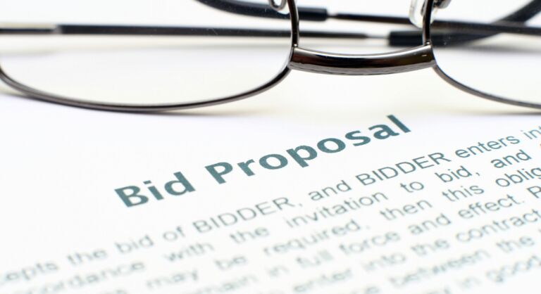 A document with the words bid proposal and a pair of glasses