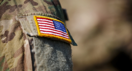 Close-up of an American flag patch on the sleeve of a military uniform.
