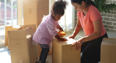 Mother Teaches African Daughter To Stick Tape On Cardboard Boxes At Home